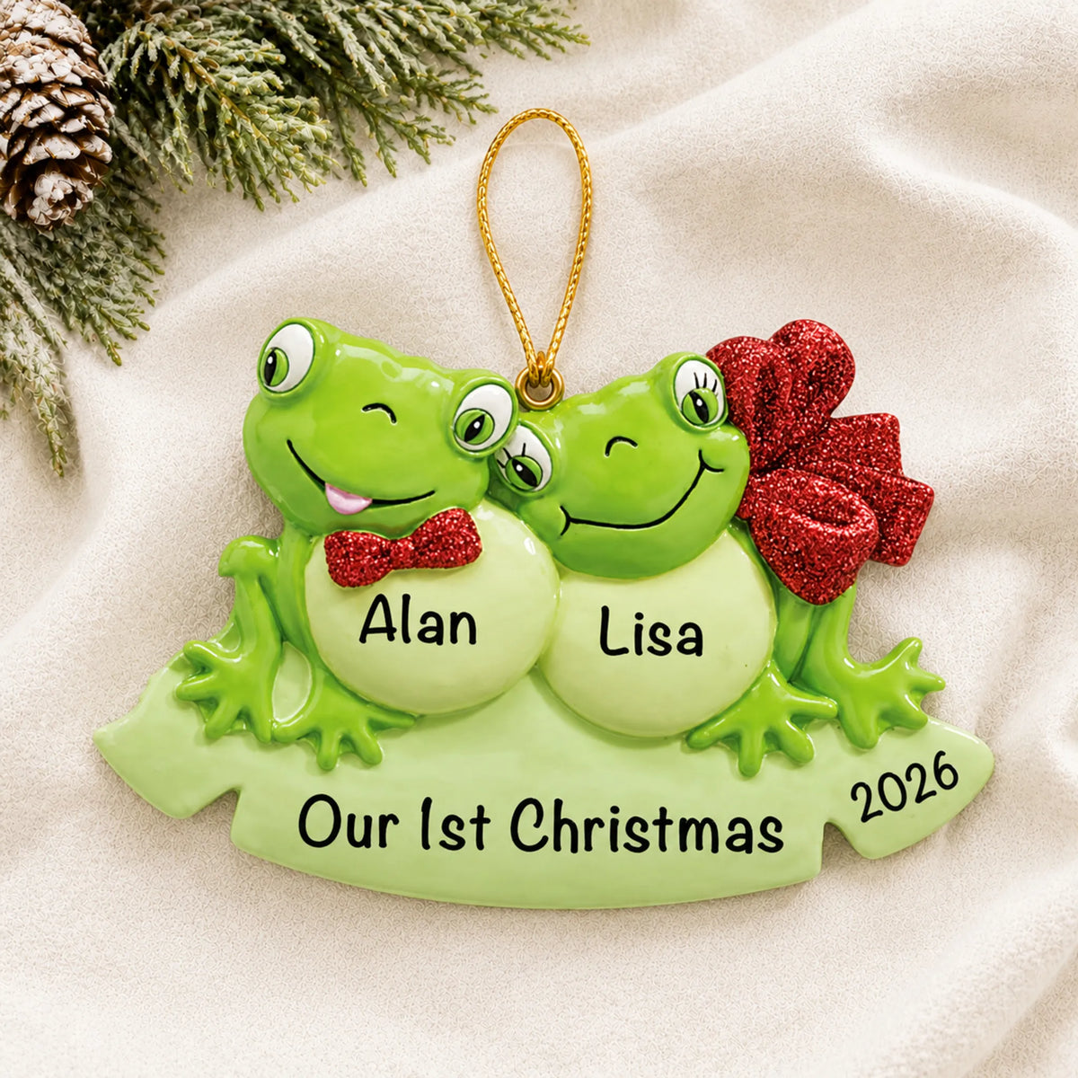 Personalized frog couple christmas ornament laid on a soft white knit blanket