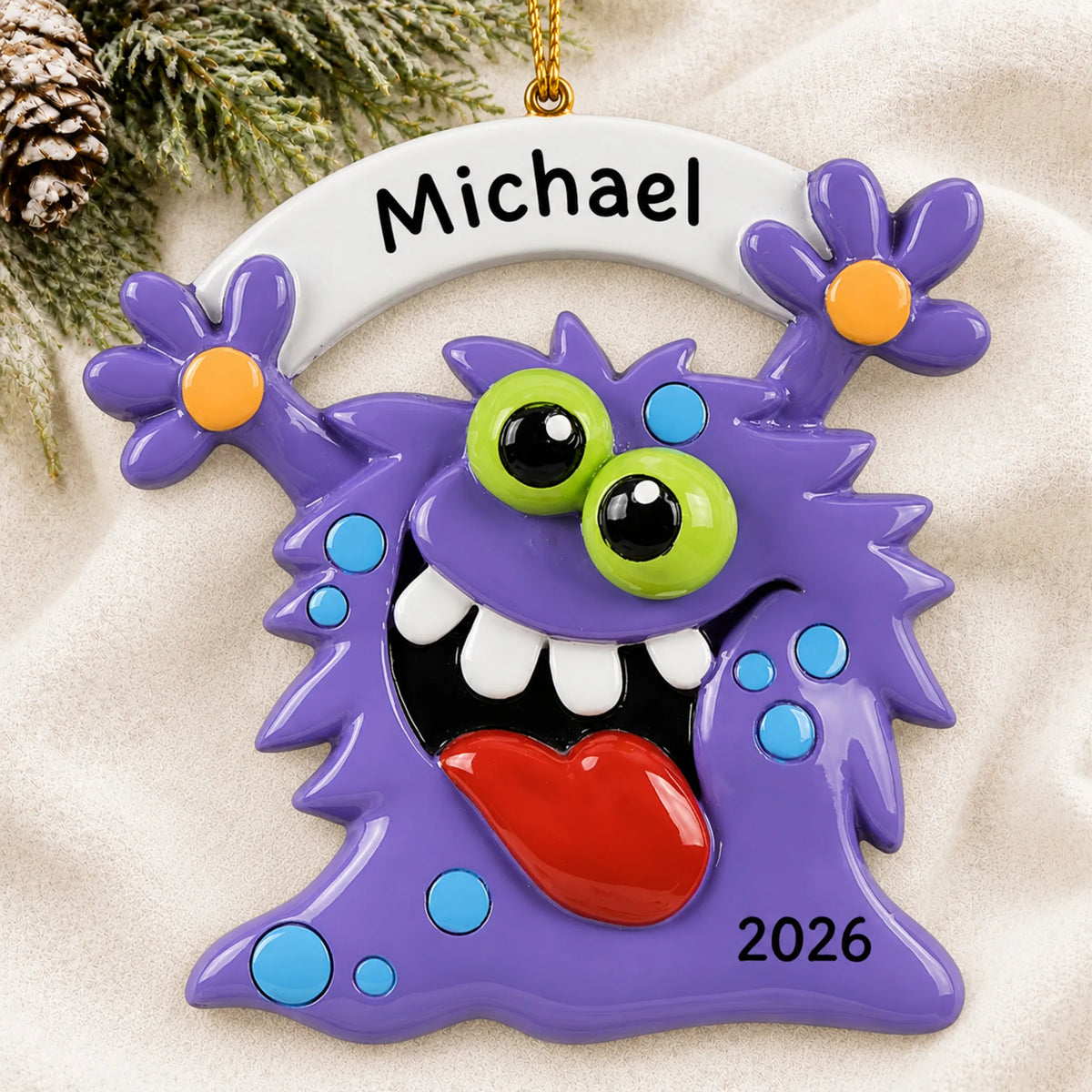 Personalized purple monster christmas ornament laid on a soft white knit blanket