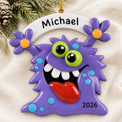 Personalized purple monster christmas ornament laid on a soft white knit blanket