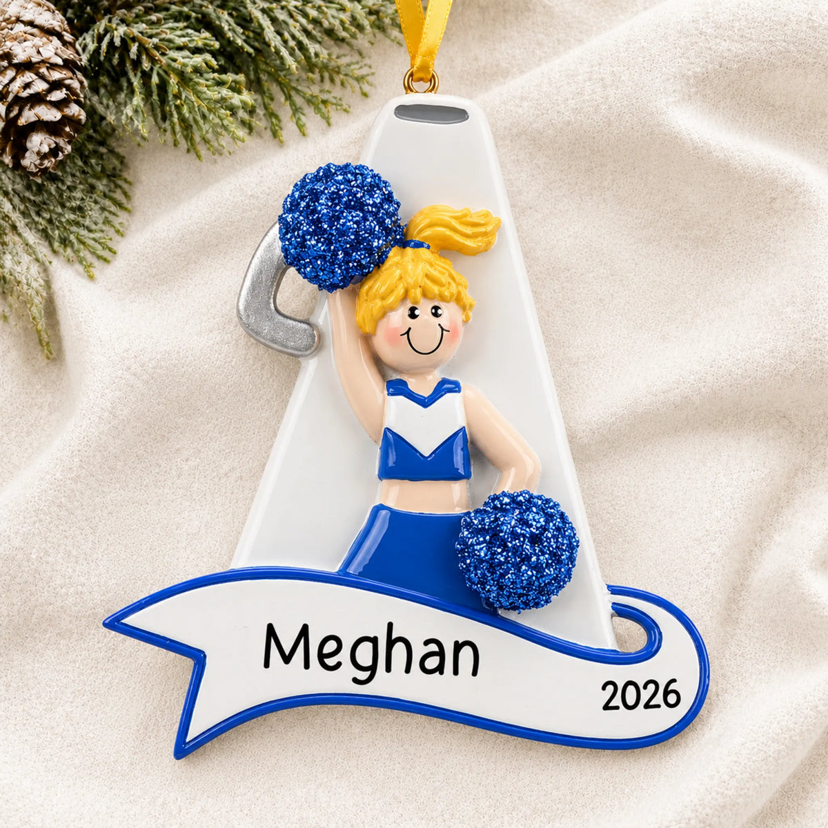 Personalized blonde cheerleader blue megaphone christmas ornament laid on a soft white knit blanket