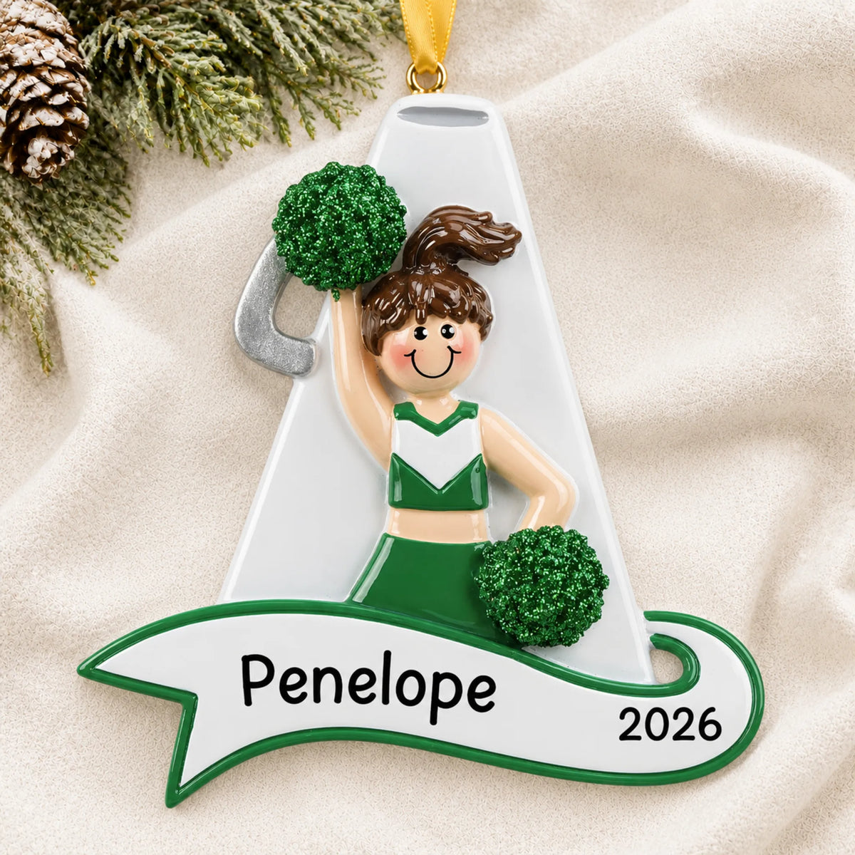 Personalized cheerleader green megaphone christmas ornament laid on a soft white knit blanket