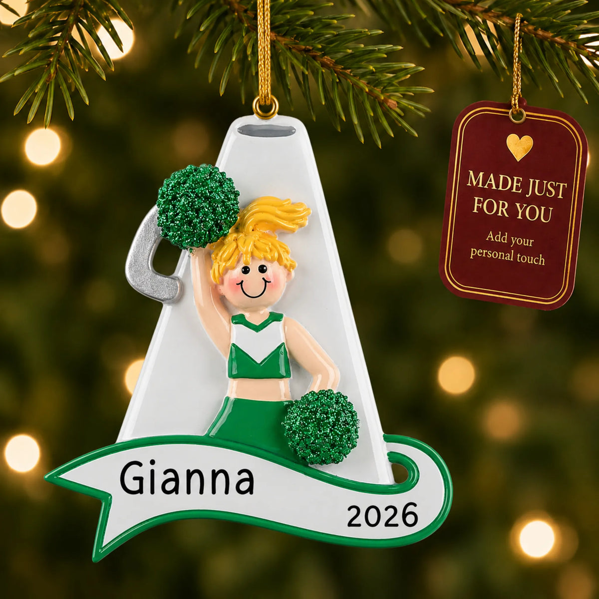 Blonde cheerleader green megaphone christmas ornament hanging on a lit Christmas tree with a Made Just For You gift tag