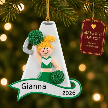 Blonde cheerleader green megaphone christmas ornament hanging on a lit Christmas tree with a Made Just For You gift tag