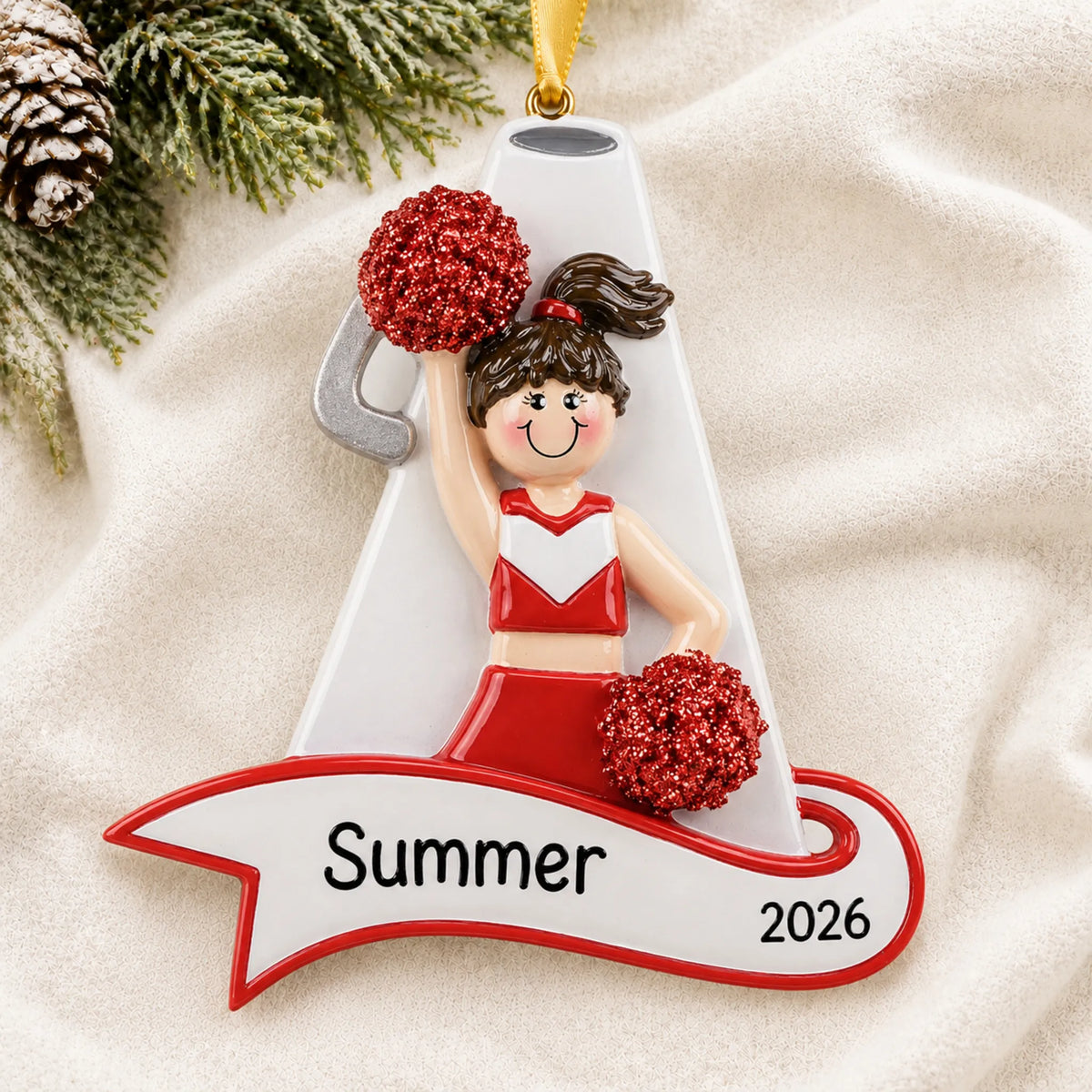 Personalized cheerleader red megaphone christmas ornament laid on a soft white knit blanket