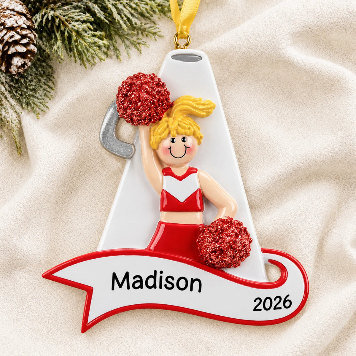 Personalized blonde cheerleader red megaphone christmas ornament laid on a soft white knit blanket