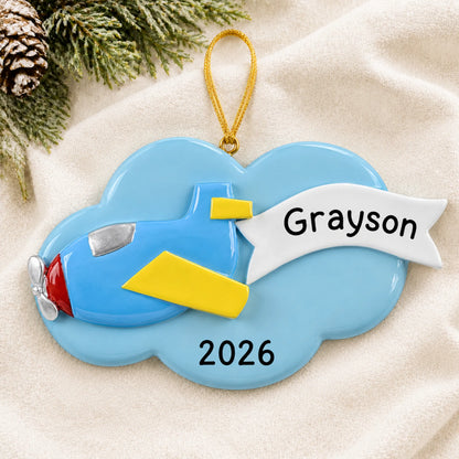 Personalized airplane christmas ornament laid on a soft white knit blanket