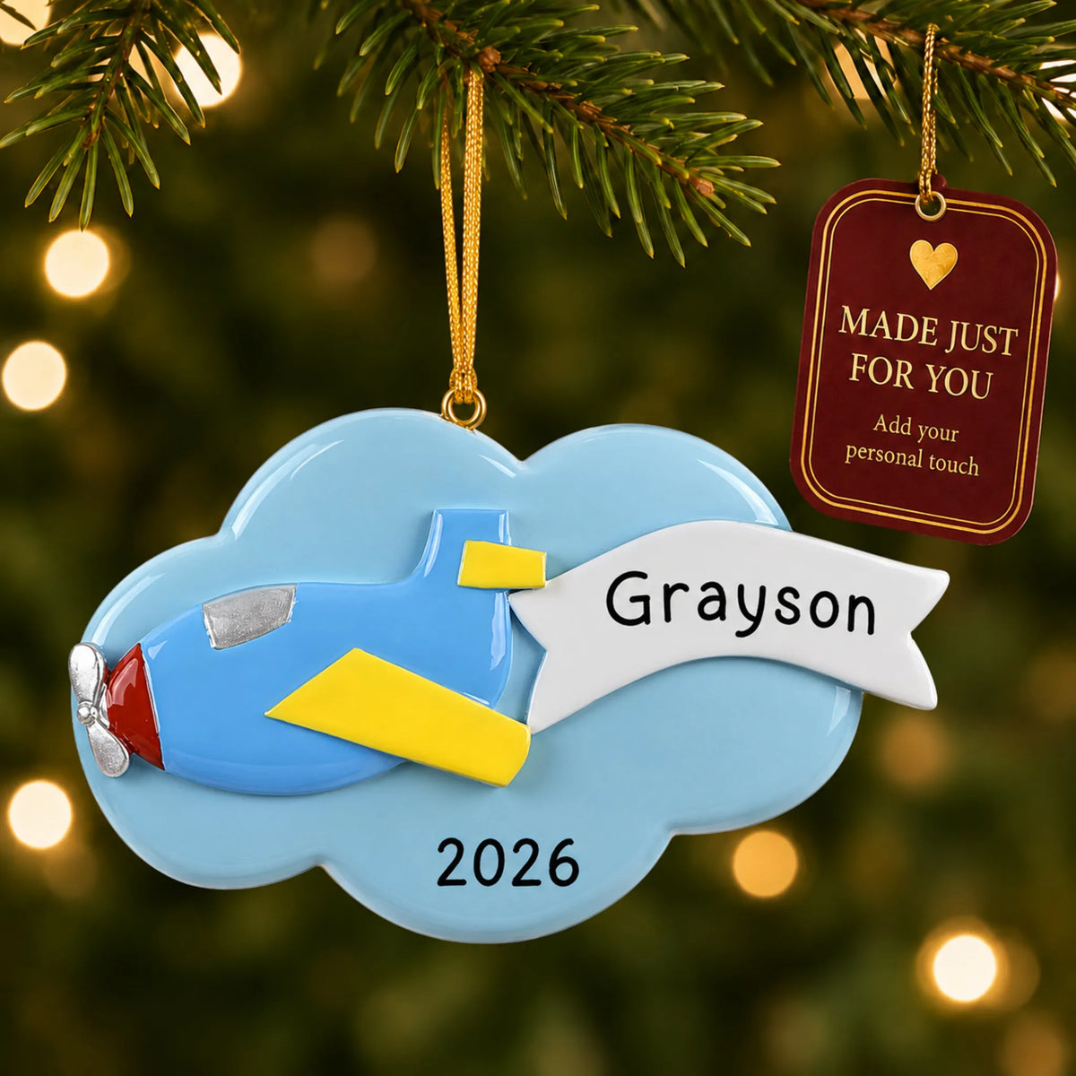 Airplane christmas ornament hanging on a lit Christmas tree with a Made Just For You gift tag
