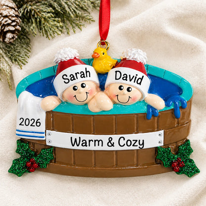 Personalized hot tub couple christmas ornament laid on a soft white knit blanket