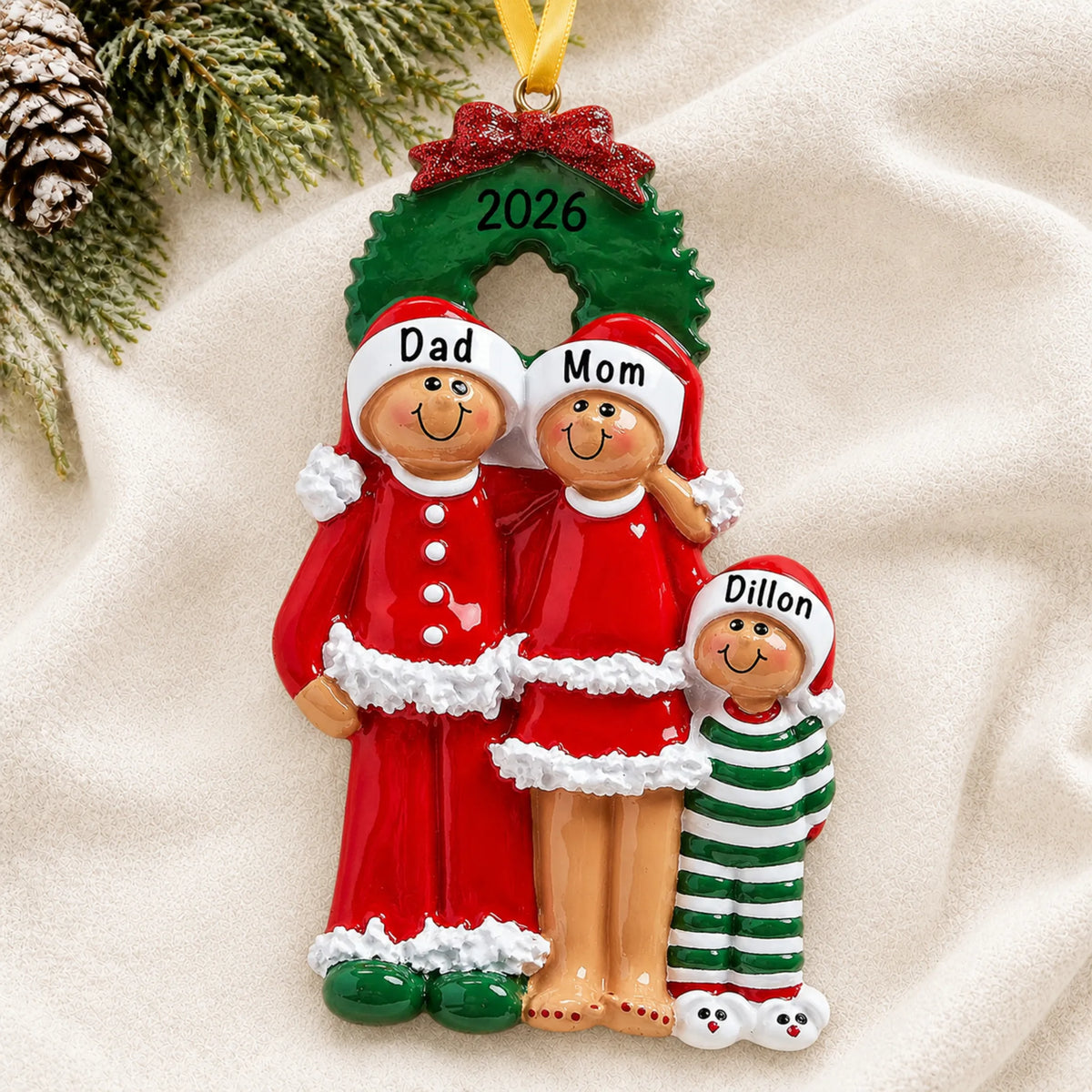 Personalized ethnic family of 3 christmas ornament laid on a soft white knit blanket