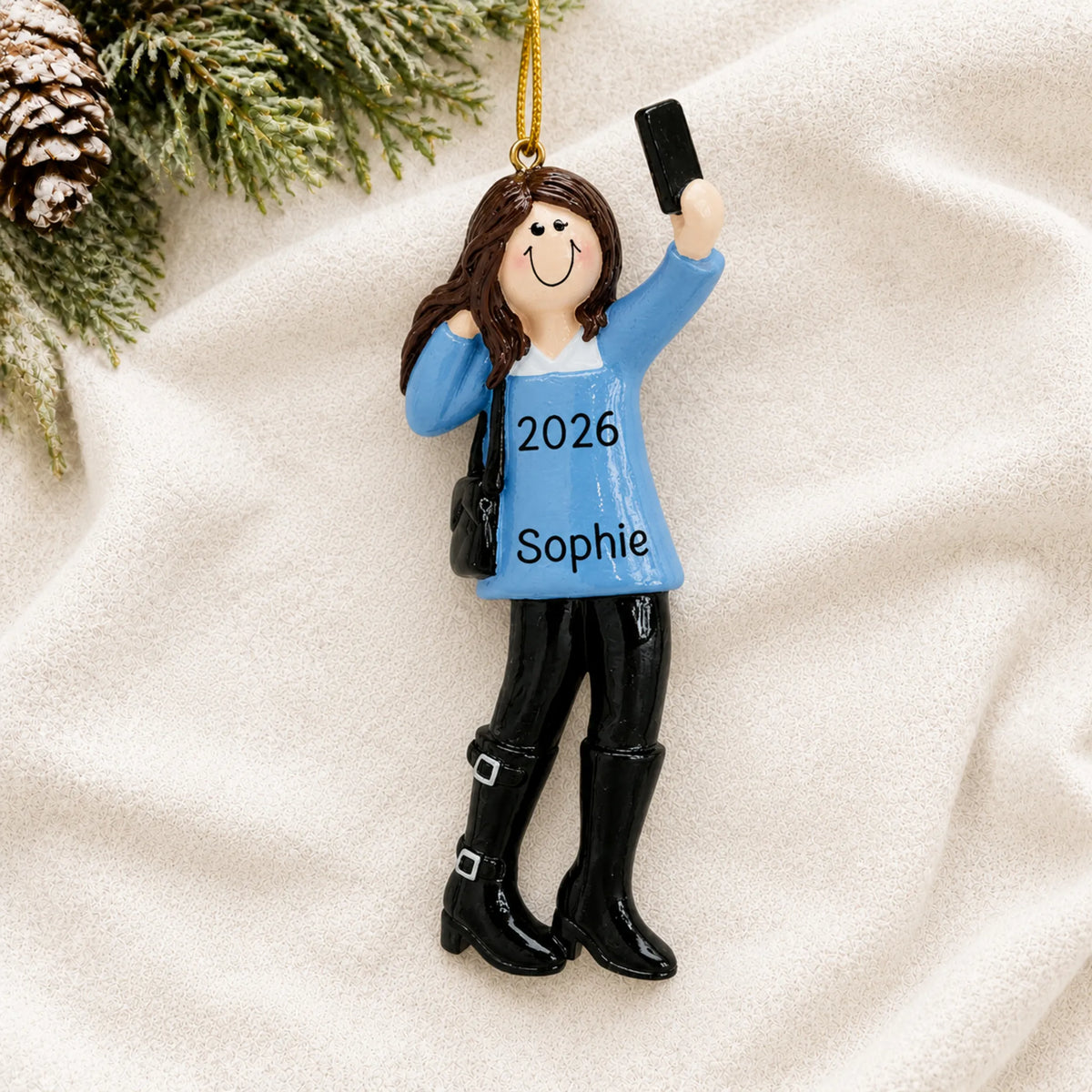 Personalized selfie girl christmas ornament laid on a soft white knit blanket