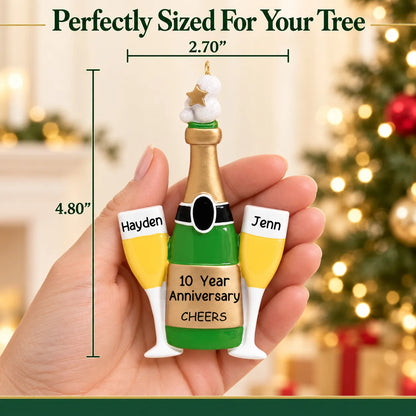 Personalized champagne anniversary Christmas ornament held in hand, about 2.7 inches wide by 4.8 inches tall
