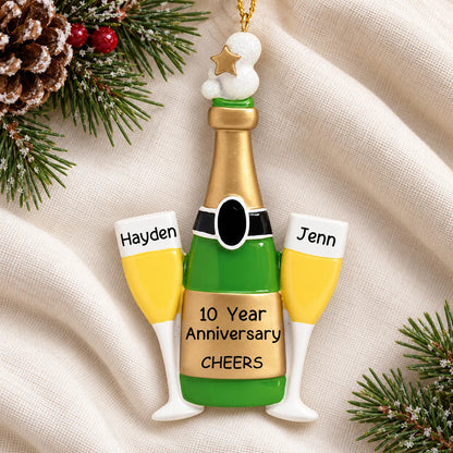Personalized champagne anniversary Christmas ornament reading Hayden, Jenn, and 10 Year Anniversary on a white knit blanket