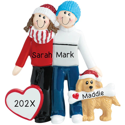 Personalized Christmas ornament featuring a couple hugging next to a dog wearing a Santa hat and holding a bone, with a blank white heart ready for custom name and year engraving.