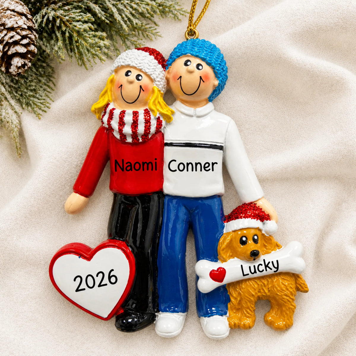 Personalized blonde couple with dog christmas ornament laid on a soft white knit blanket