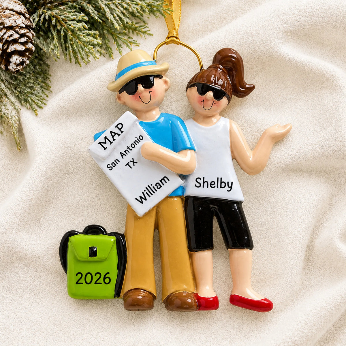 Personalized travel couple christmas ornament laid on a soft white knit blanket