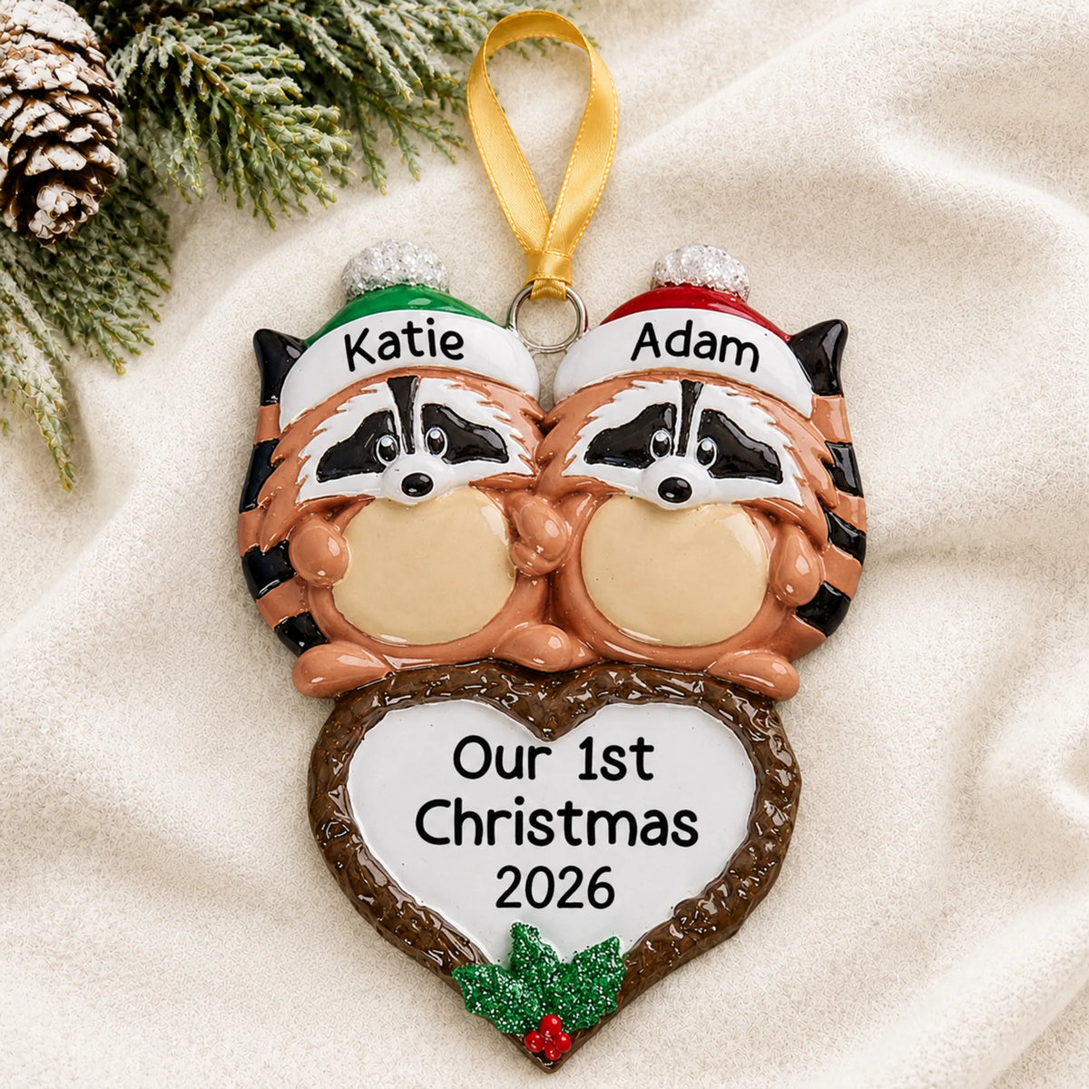 Personalized raccoon couple christmas ornament laid on a soft white knit blanket