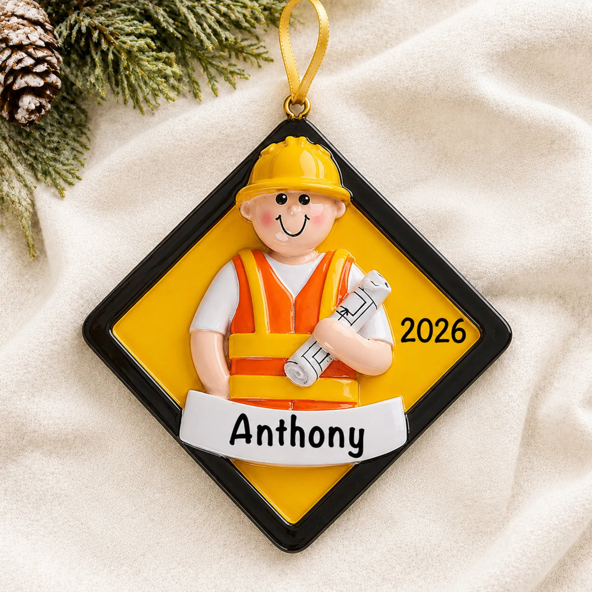Personalized construction worker christmas ornament laid on a soft white knit blanket