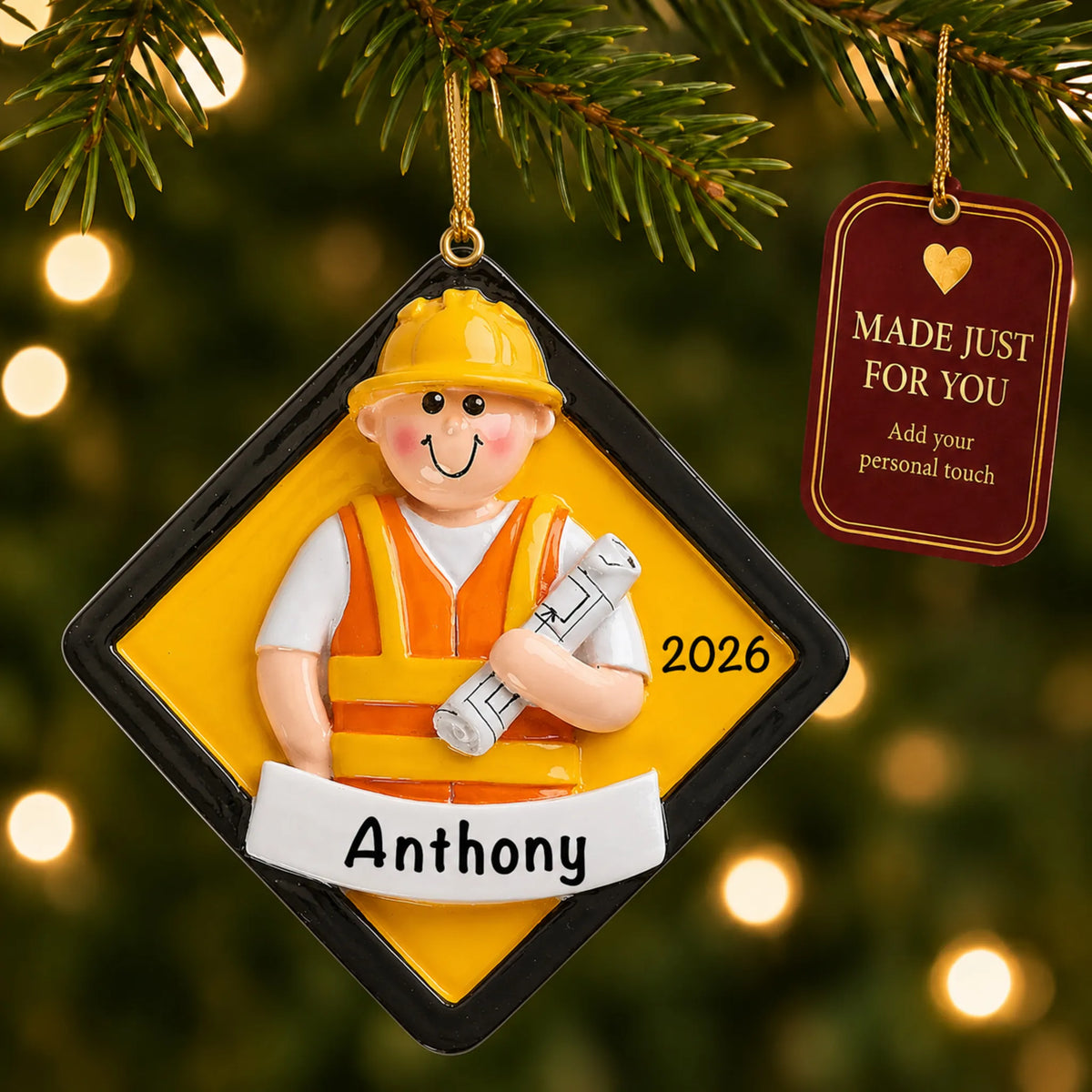 Construction worker christmas ornament hanging on a lit Christmas tree with a Made Just For You gift tag