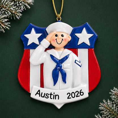 Personalized Navy sailor USA shield Christmas ornament with name and year, shown on a green holiday background