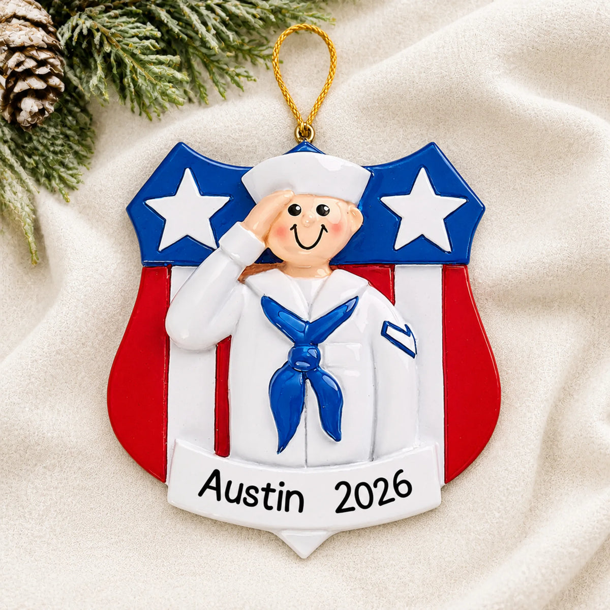 Personalized Navy sailor USA shield Christmas ornament shown on a soft white blanket