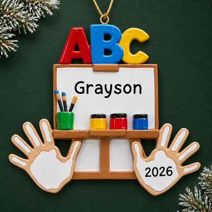 Personalized kindergarten ABC Christmas ornament with name and year, shown on a green holiday background