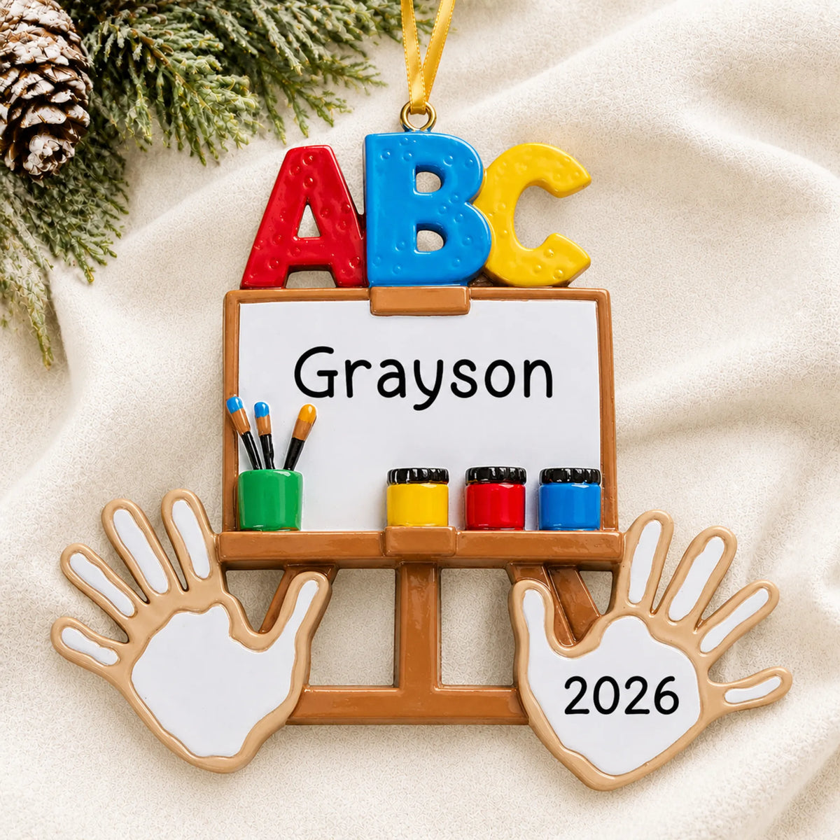 Personalized kindergarten ABC Christmas ornament shown on a soft white blanket