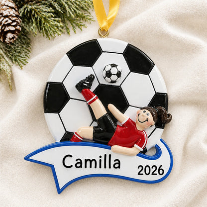 Personalized soccer kick girl christmas ornament laid on a soft white knit blanket