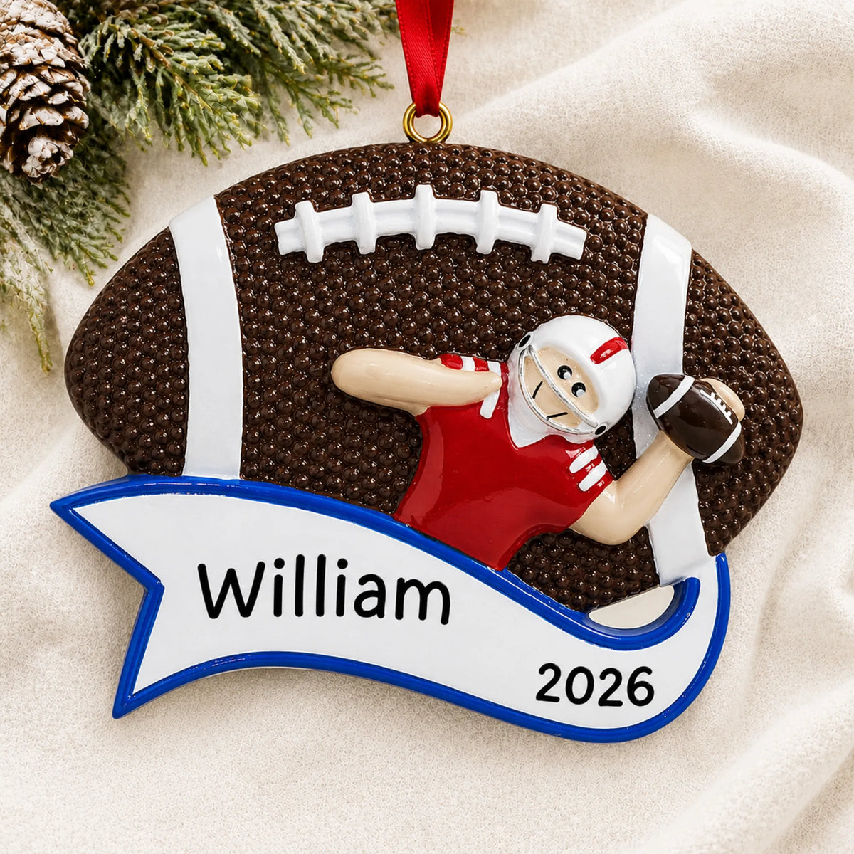 Personalized football quarterback christmas ornament laid on a soft white knit blanket