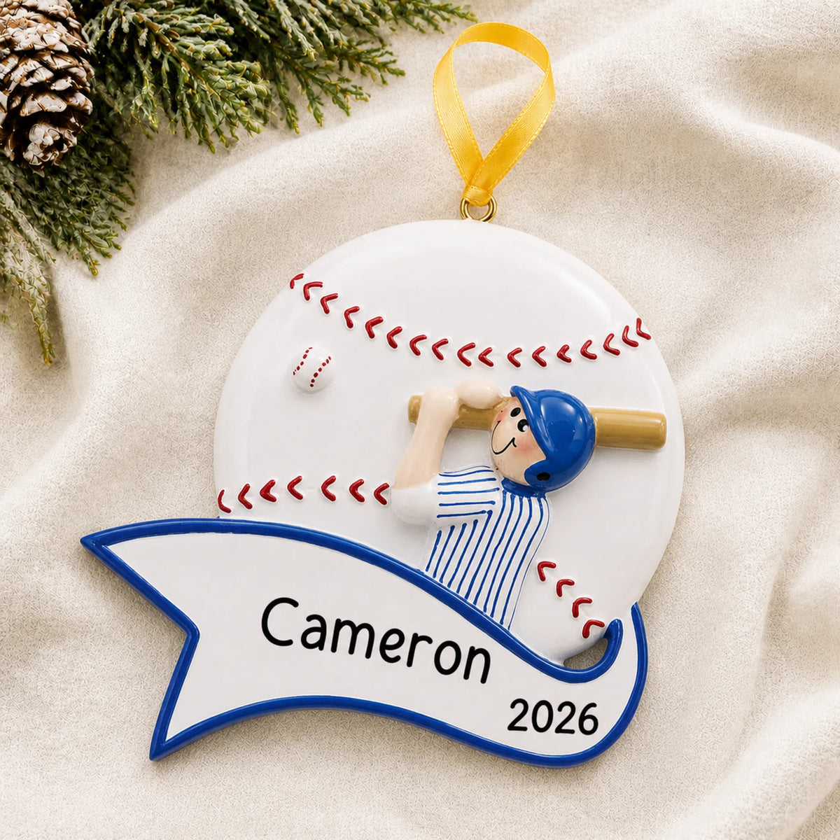 Personalized baseball boy swing christmas ornament laid on a soft white knit blanket