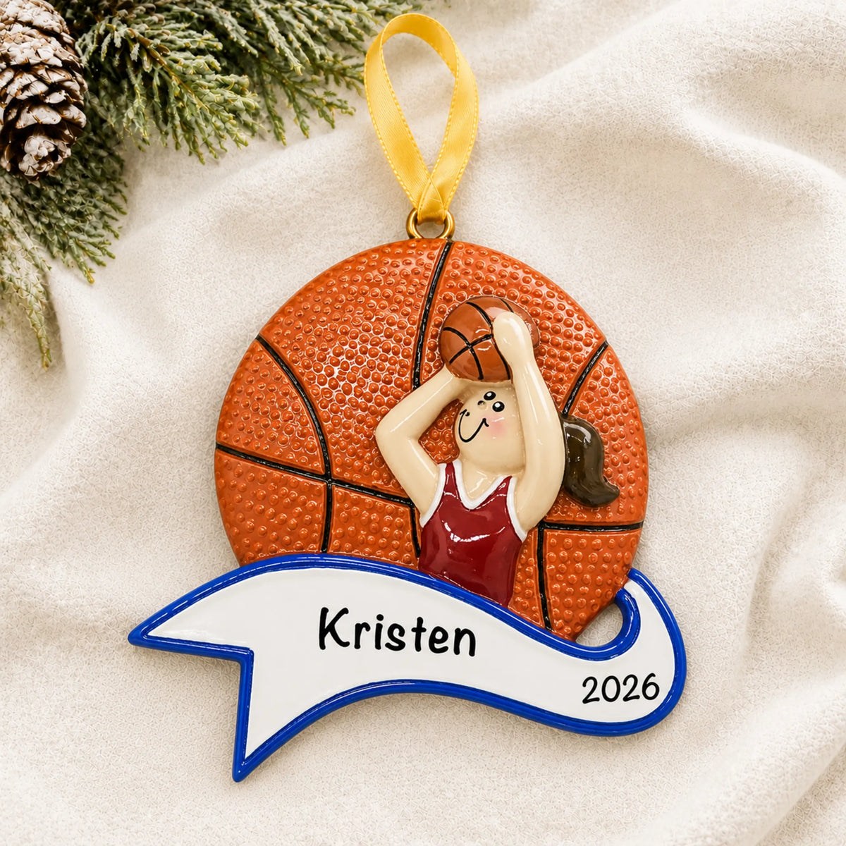 Personalized basketball shot girl christmas ornament laid on a soft white knit blanket