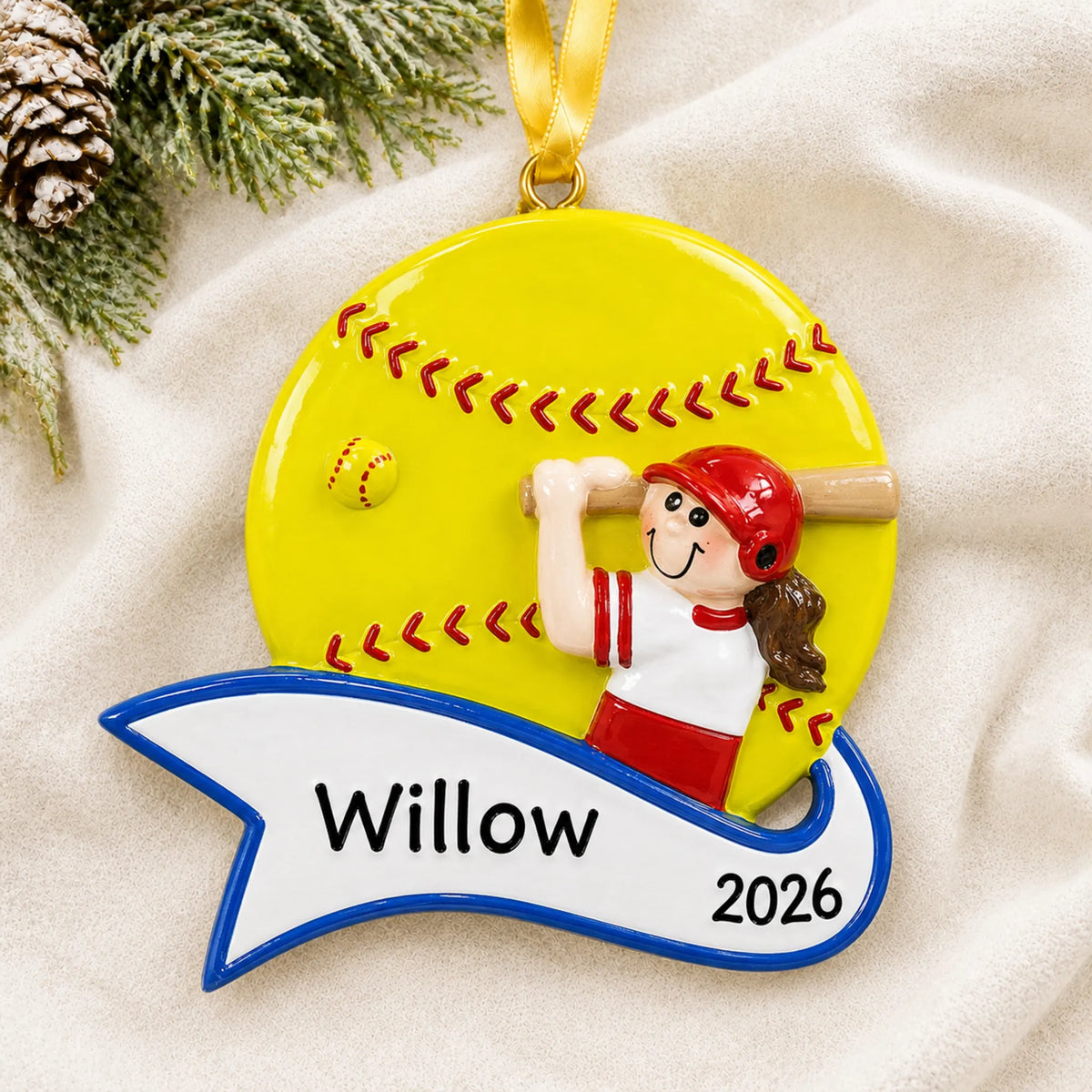 Personalized softball batter girl christmas ornament laid on a soft white knit blanket