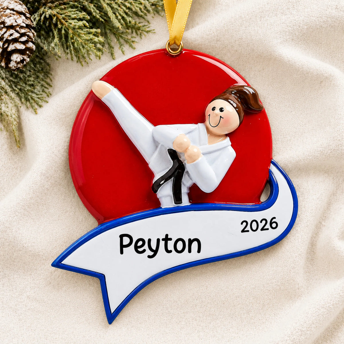 Personalized karate kick girl christmas ornament laid on a soft white knit blanket