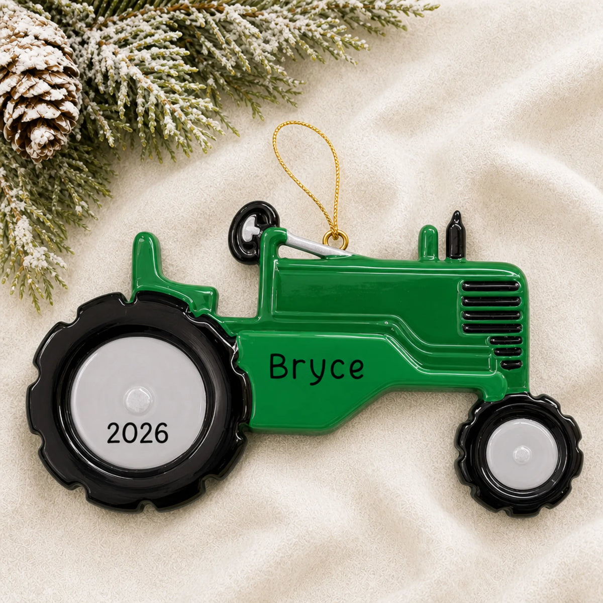 Personalized green tractor christmas ornament laid on a soft white knit blanket