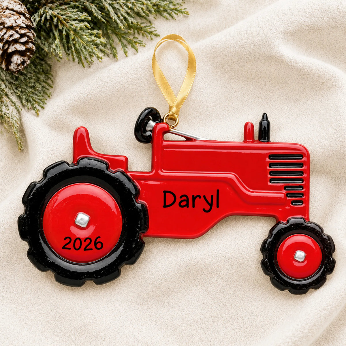 Personalized red tractor christmas ornament laid on a soft white knit blanket