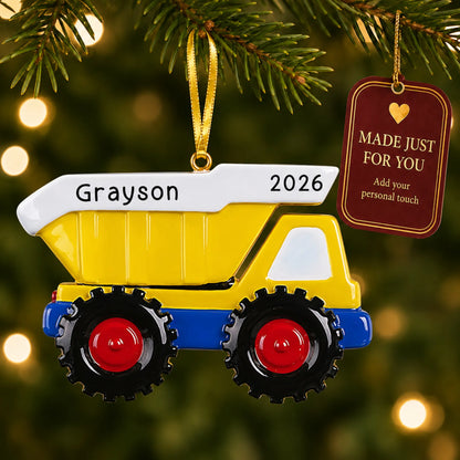 Yellow kids dump truck christmas ornament hanging on a lit Christmas tree with a Made Just For You gift tag