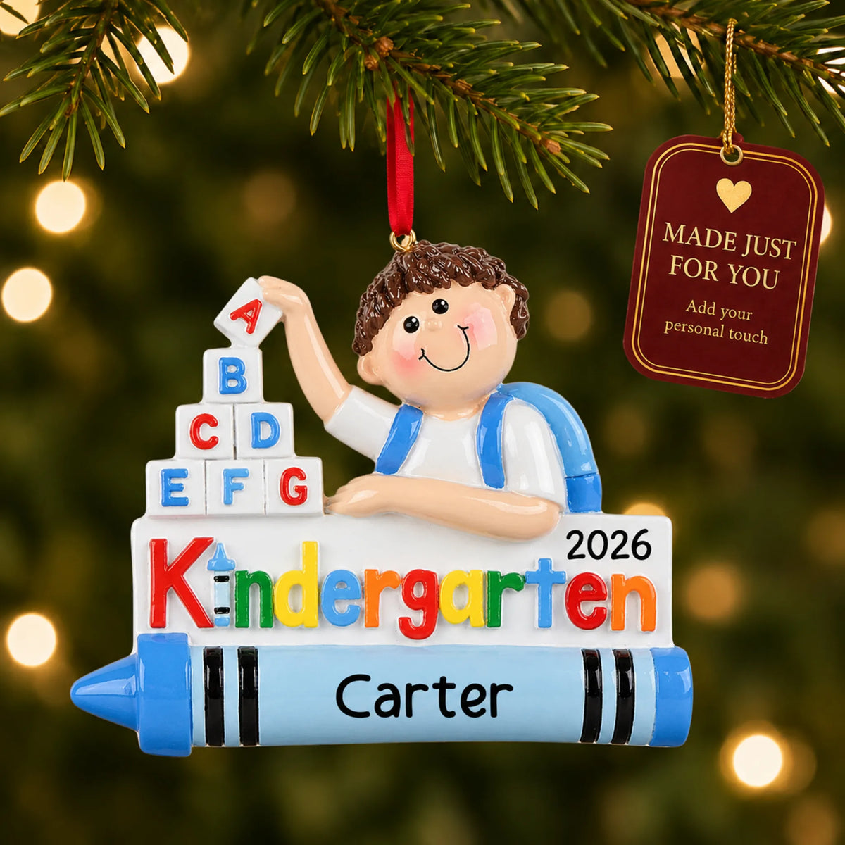 Personalized kindergarten boy Christmas ornament hanging among tree lights with a Made Just For You tag