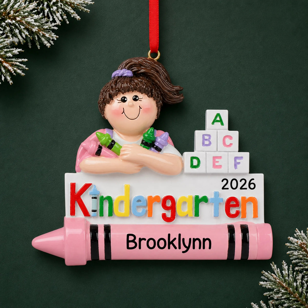 Personalized kindergarten girl Christmas ornament with name and year, shown on a green holiday background