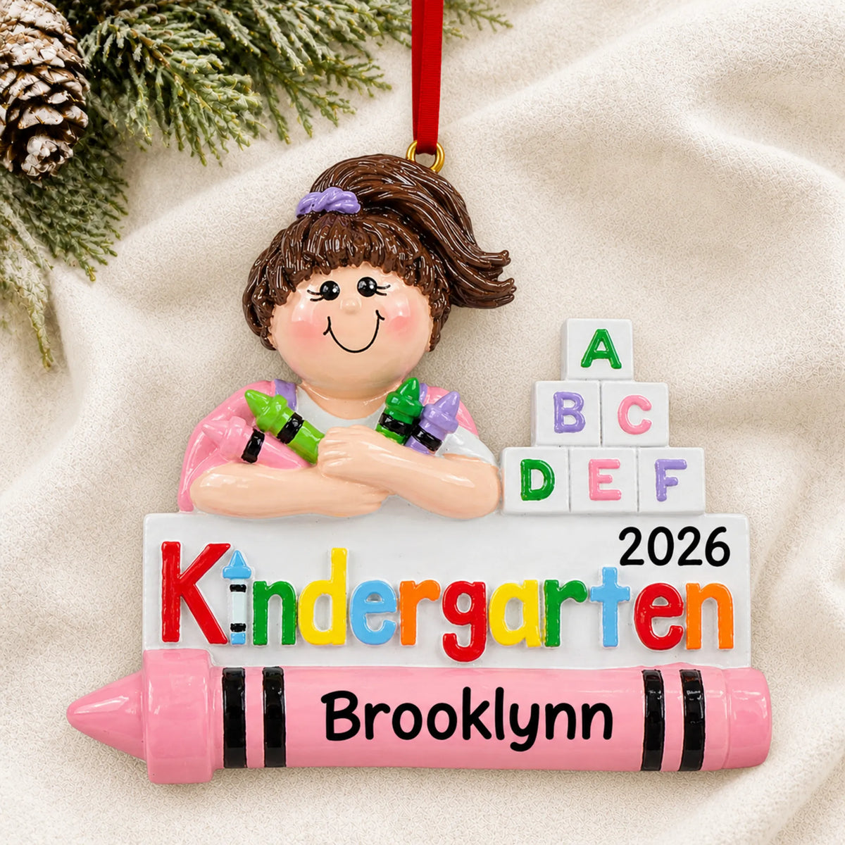 Personalized kindergarten girl Christmas ornament shown on a soft white blanket