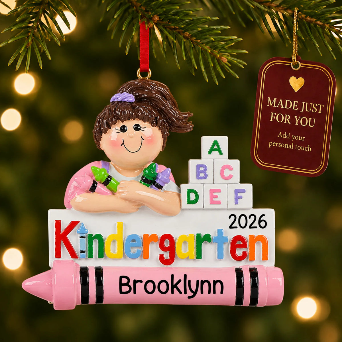 Personalized kindergarten girl Christmas ornament hanging among tree lights with a Made Just For You tag