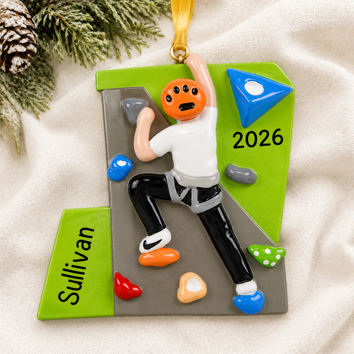 Personalized rock climber guy christmas ornament laid on a soft white knit blanket