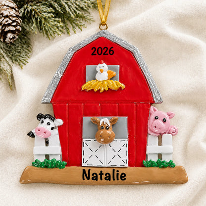 Personalized red barn farm animals christmas ornament laid on a soft white knit blanket