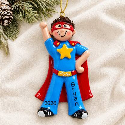 Personalized super hero boy christmas ornament laid on a soft white knit blanket