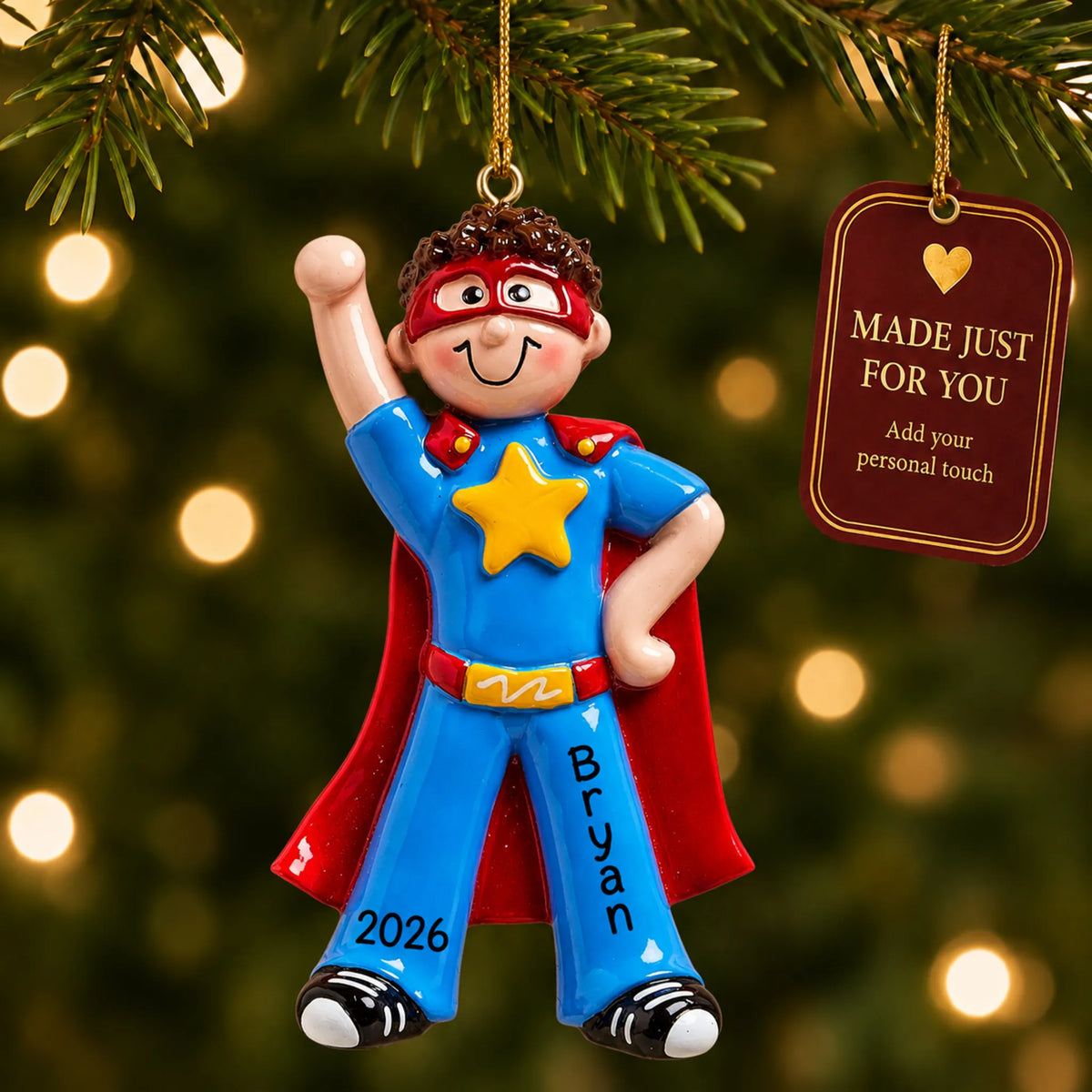 Super hero boy christmas ornament hanging on a lit Christmas tree with a Made Just For You gift tag