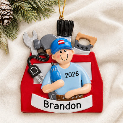 Personalized handyman toolbox christmas ornament laid on a soft white knit blanket