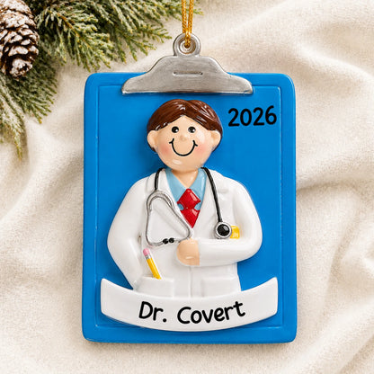 Personalized doctor guy clipboard christmas ornament laid on a soft white knit blanket