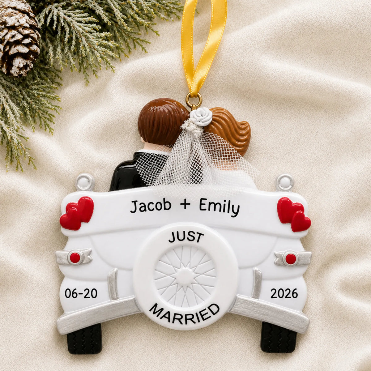 Personalized Just Married wedding car Christmas ornament on a cream knit blanket beside pine and pinecones