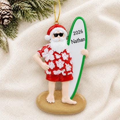Personalized Santa surfboard christmas ornament laid on a soft white knit blanket