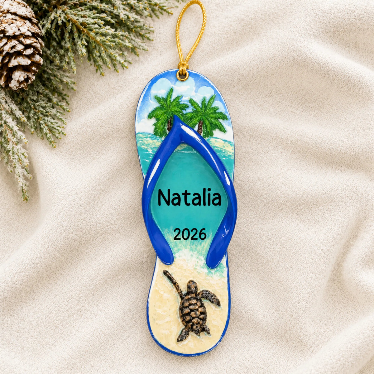 Personalized turtle island flip flop christmas ornament laid on a soft white knit blanket