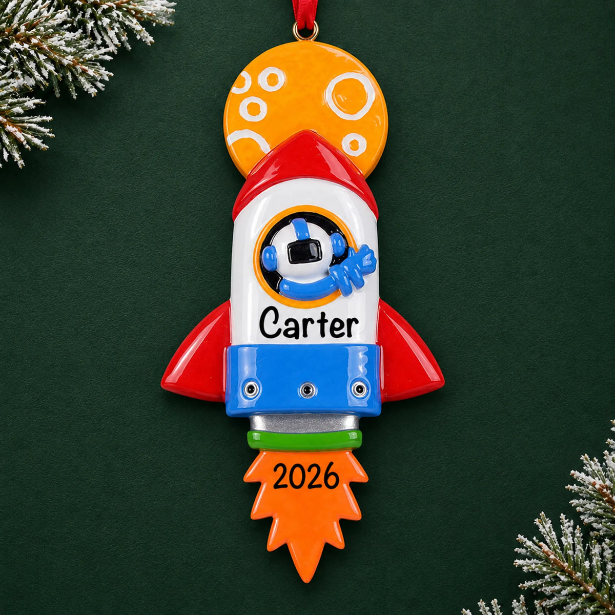 Personalized space rocket christmas ornament on a dark green pine background