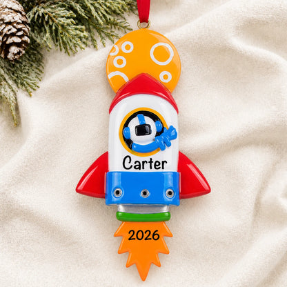Personalized space rocket christmas ornament laid on a soft white knit blanket